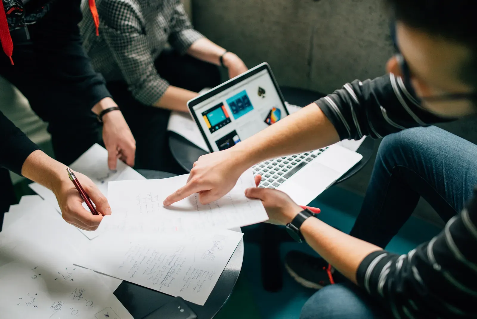 “A group of people brainstorming over a laptop and sheets of paper” by Štefan Štefančík on Unsplash
