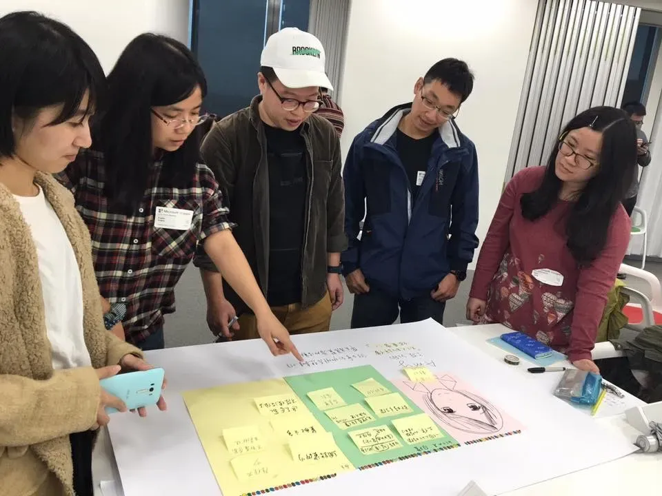 設計讀書會上，大家圍著桌上的便利貼討論
